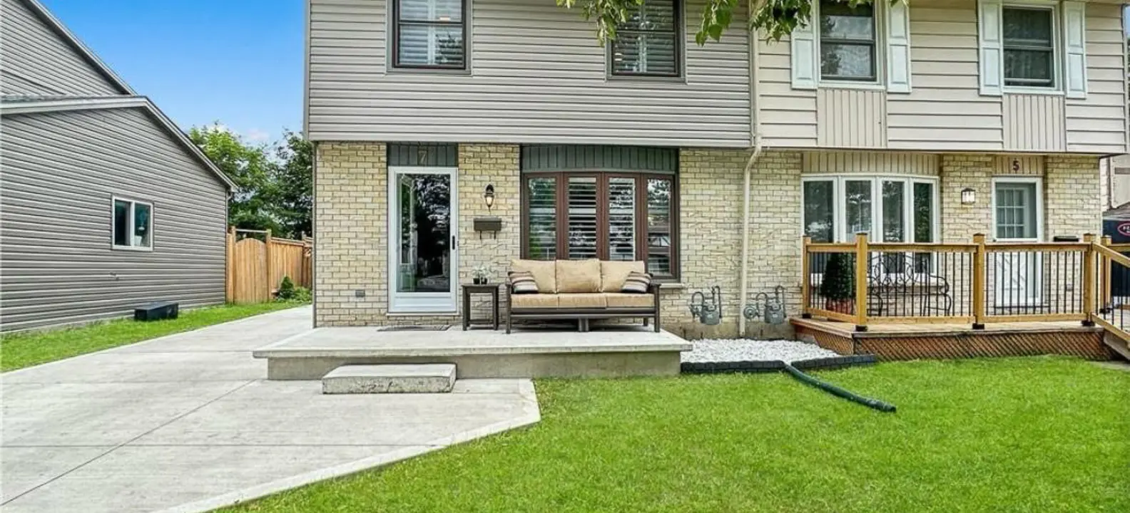 The back of a semi-detached home, with a patio, deck and green lawn