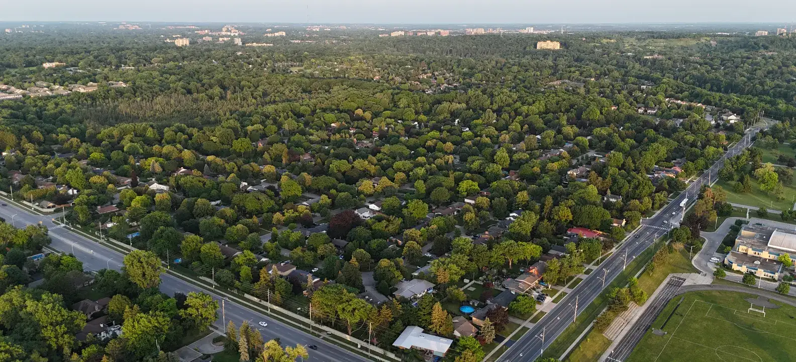 Looking north over Hyde Park in London, Ontario: a leafy neighbourhood between two main roads, with a sports field in the corner